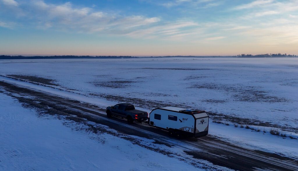 Ford F250 puling S195 through a snowy covered field and road.