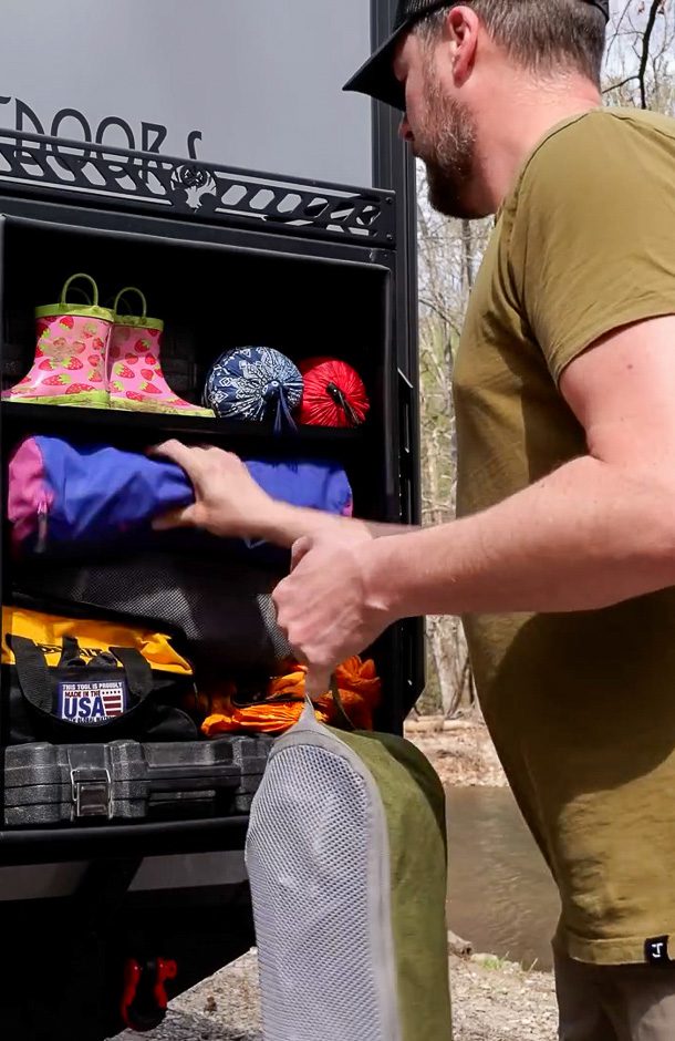 Dad packing up the rear box of the Imperial Outdoors X195 trailer with this families camping accessories.