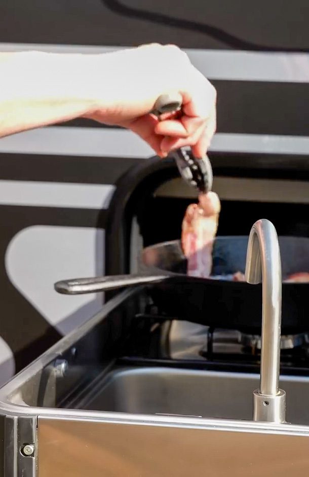 Cooking bacon on the pull out kitchen on the X195 made by Imperial Outdoors.