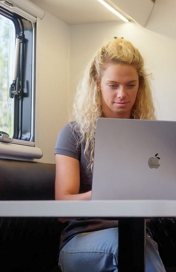 Woman working remotely in the off grid Imperial Outdoors camper.
