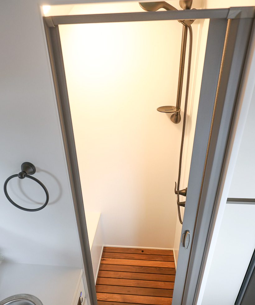 Stand up shower with stainless steel base and a teak wood floor in the Imperial Outdoors Sport Series off grid camper.
