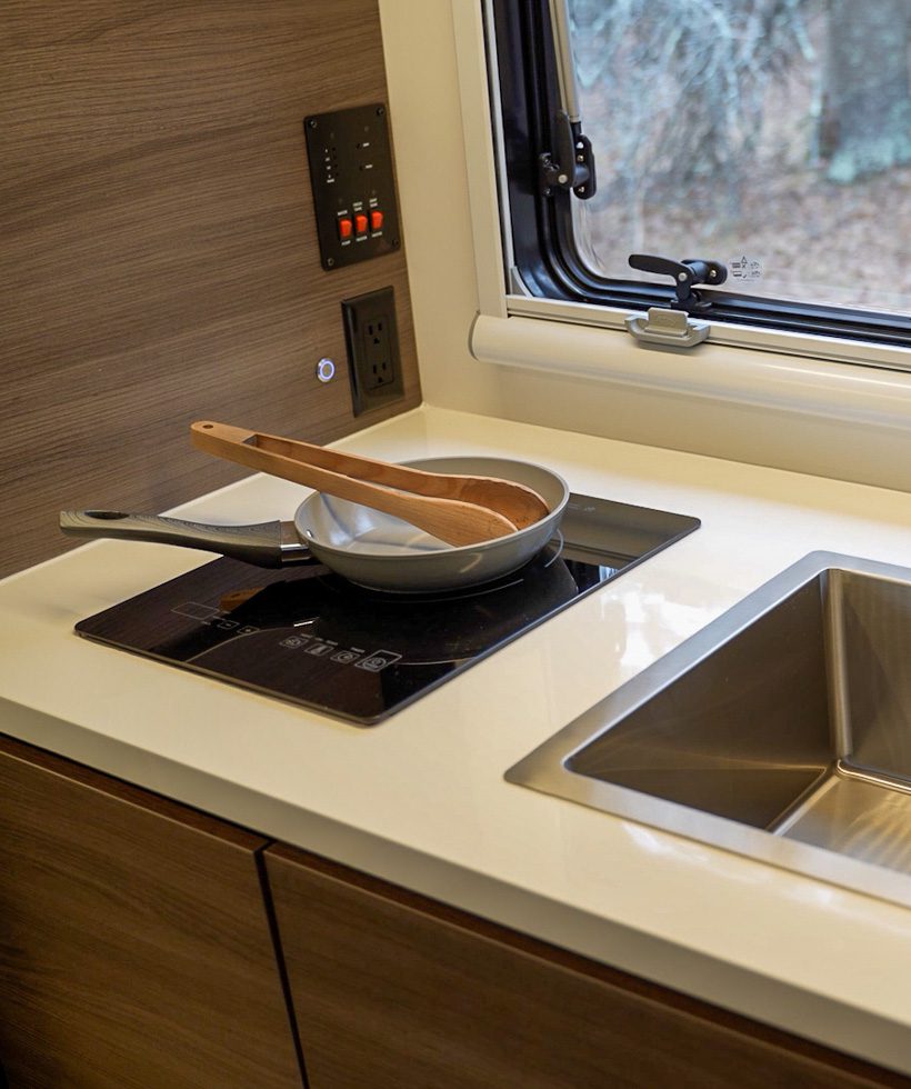 Pan and spoon sitting on the induction cooktop in the Imperial Outdoors X145 off grid RV.