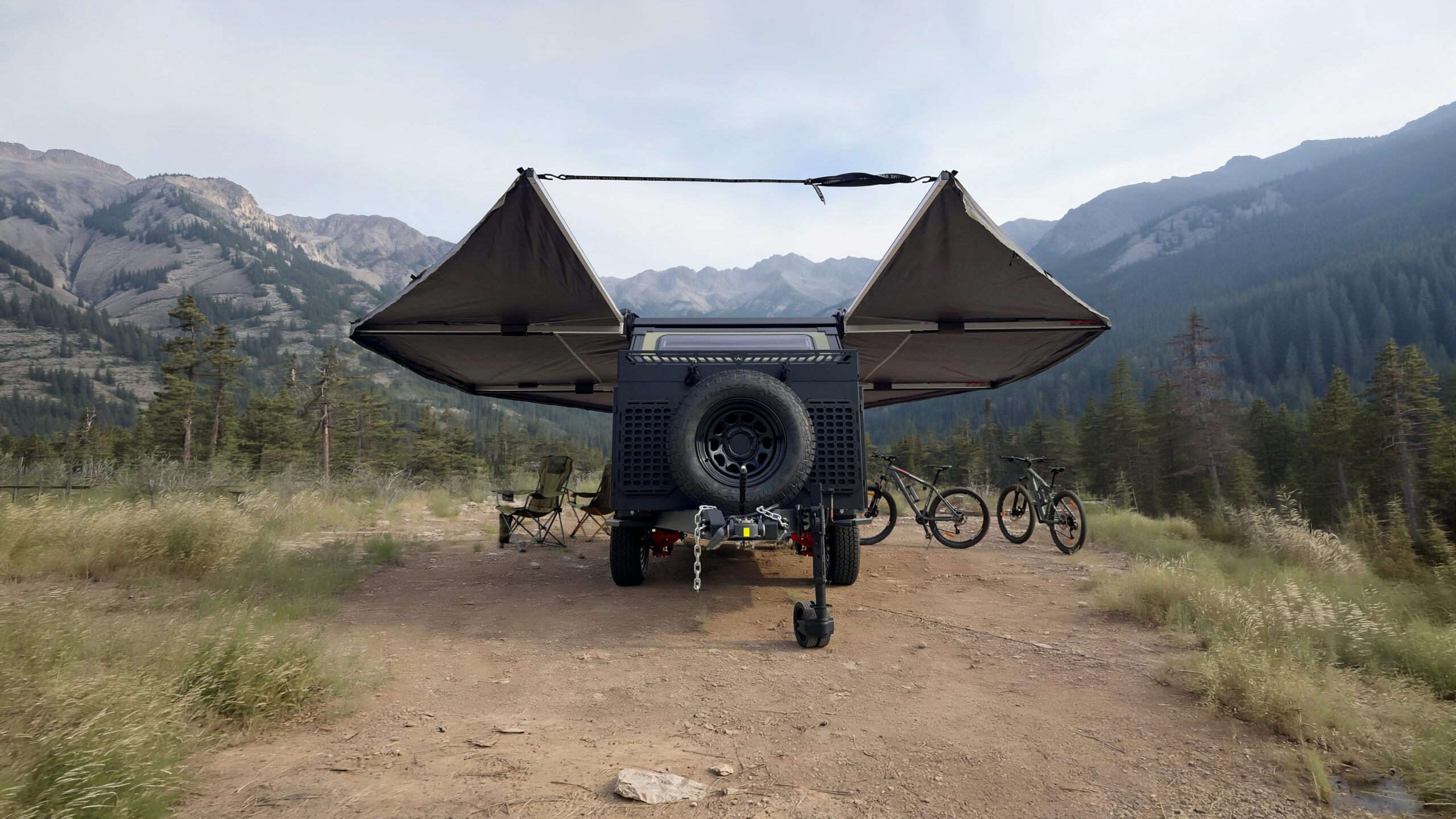 Mountain biking in a Imperial Outdoors Outback Series OB120 off grid camping with awnings deployed in the mountains.
