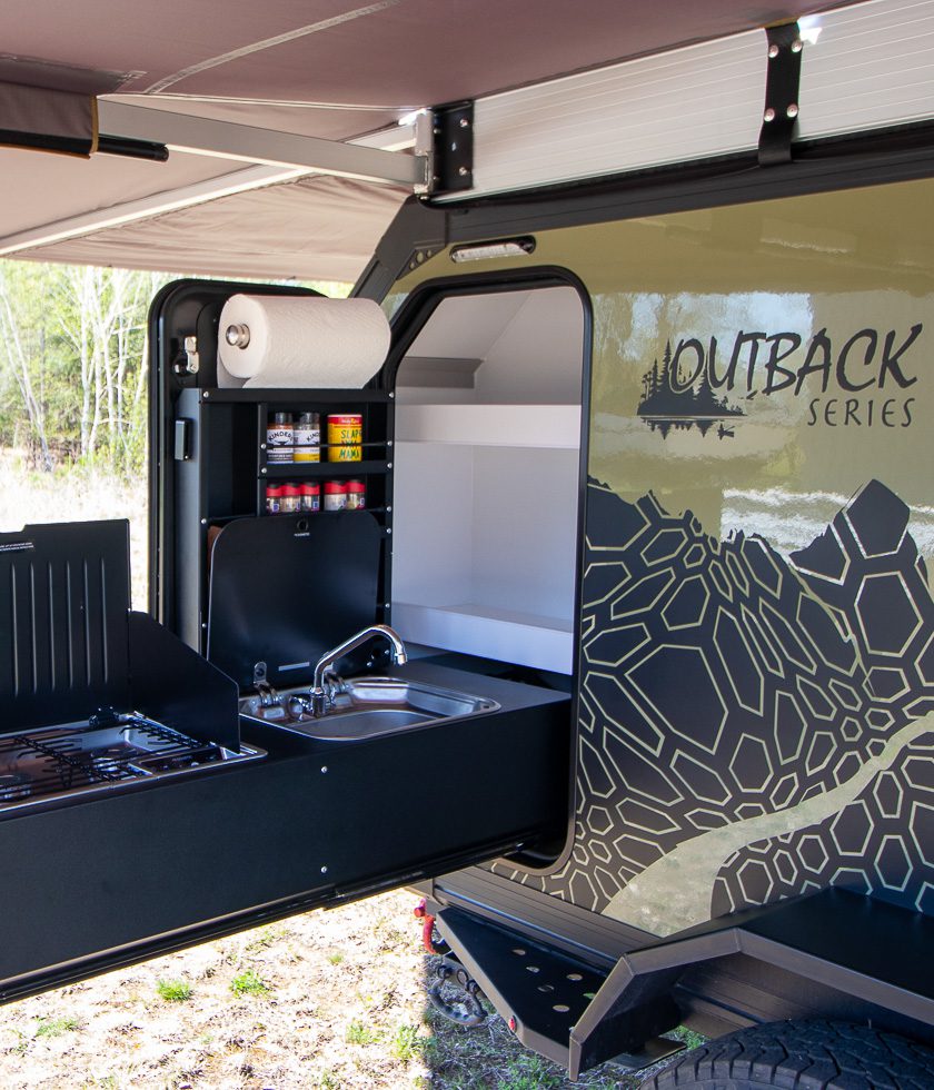 The pullout kitchen is in the rear of the OB120 that has a sink, 2 burner cooktop, and spice rack storage.