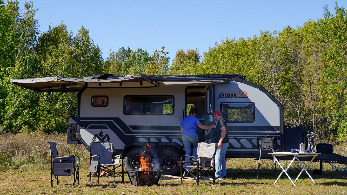Couple setting of an off grid camping spot with fire with an Imperial Outdoors Xplore Series X195.