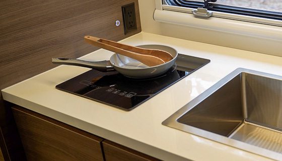 Single induction cooktop with a pan and utensil on it in the 145 from Imperial Outdoors.
