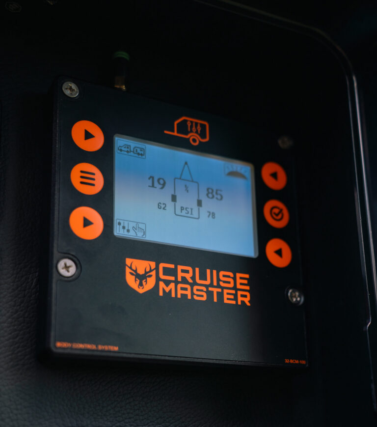 A close-up of a CRUISE MASTER control panel with orange buttons and a digital display showing PSI readings, vehicle icons, and other indicators. Below it, a label reads DUAL SUPPLY..
